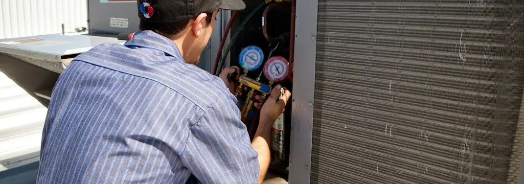 HVAC technician servicing a condenser unit in Le Ray