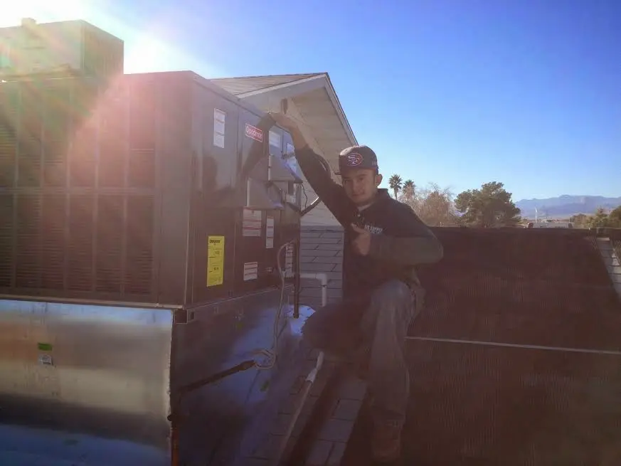 HVAC technician performing Boiler Repair on a rooftop unit in Le Ray